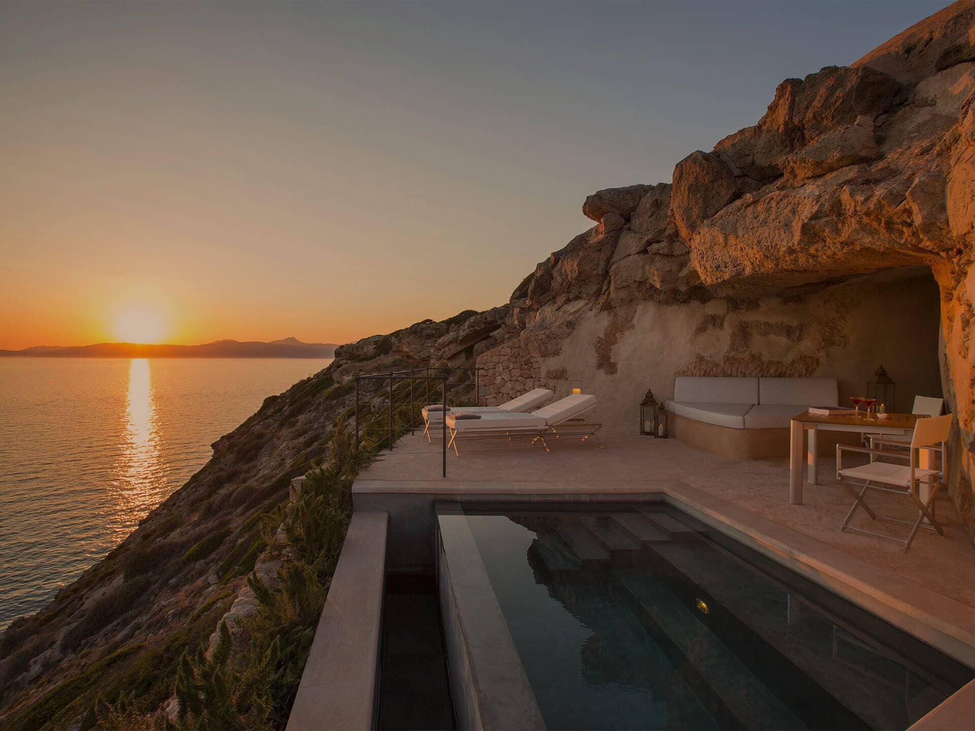 A Sentinella suite at Cap Rocat at sunset — a private plunge pool on a stone terrace cut into the cliff, sun setting over the Bay of Palma.