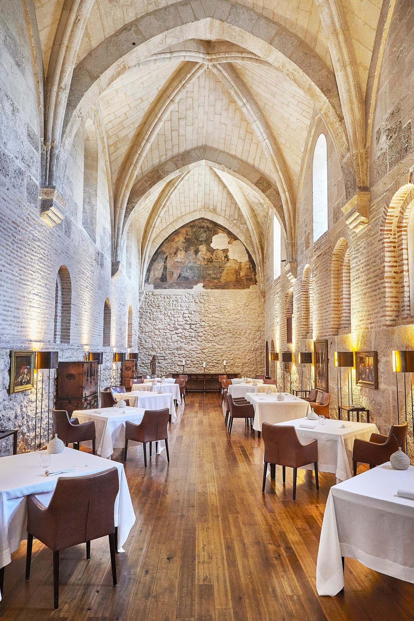 The Refectorio dining room at Abadía Retuerta — high vaulted ceiling, a single fresco at the back, white-cloth tables down the room.