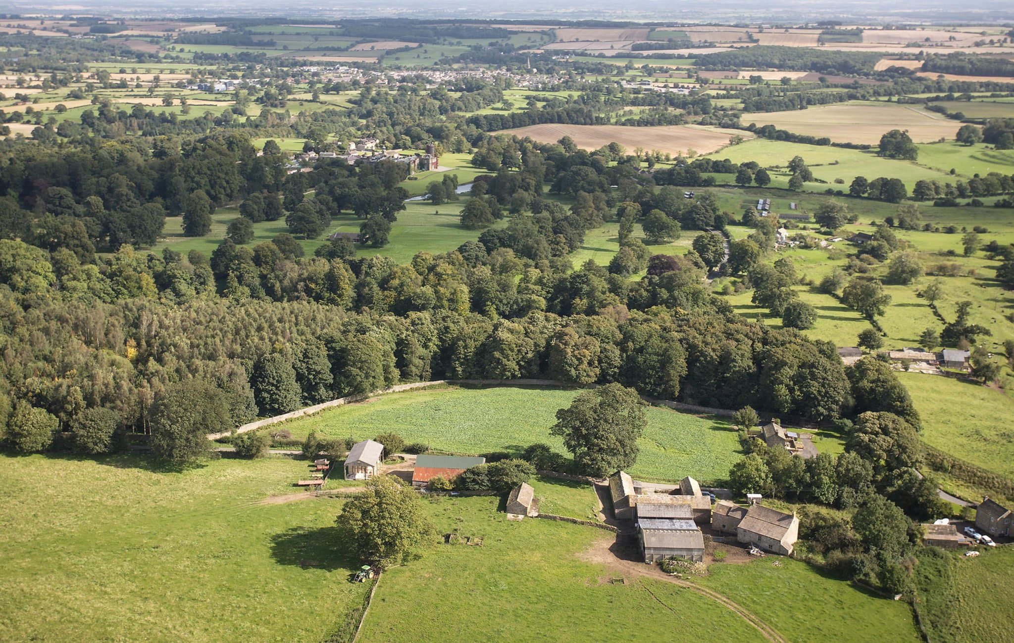 The wider Swinton Estate seen from a rise — parkland, lake and woodland under a soft Yorkshire sky.